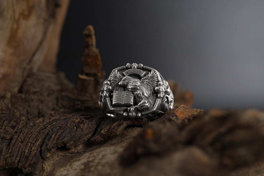 St. John eagle signet ring, sterling silver Christian jewelry, symbolic religious statement band, and handcrafted bold accessory designed for those who are drawn to faith, wisdom, and spiritual strength. This striking ring features a detailed eagle motif inspired by Saint John symbolism, framed within a bold signet structure that creates a look both sacred and powerful.