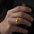 May include: A gold ring with a floral design. The ring is worn on a finger and has a detailed pattern of flowers and leaves. The ring is a bright, shiny gold color.