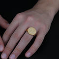 May include: A gold-colored signet ring with the words "DICKINSON COLLEGE" encircling a compass rose design. The ring is worn on a finger, showcasing its polished finish and detailed engraving. The ring is a classic piece of jewelry.